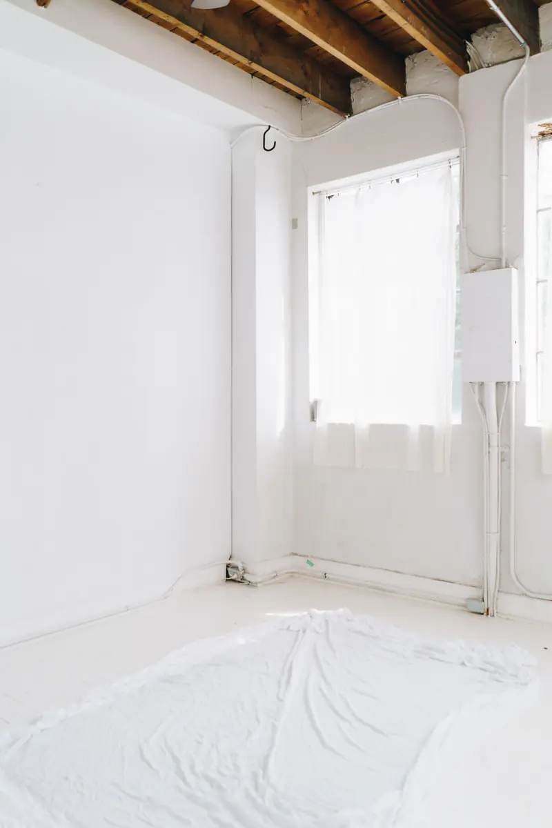An empty room with white walls and protective floor covering during renovation