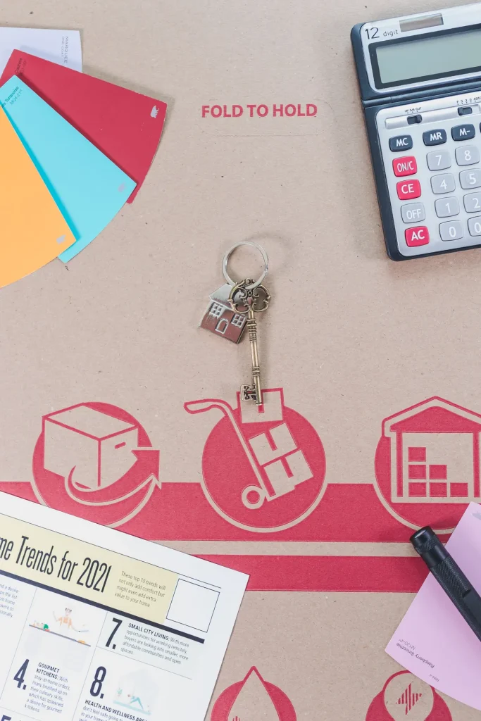 House keys, a calculator and colour samples on a cardboard moving box