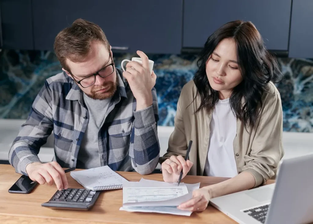 A couple reviewing household bills with a calculator and laptop