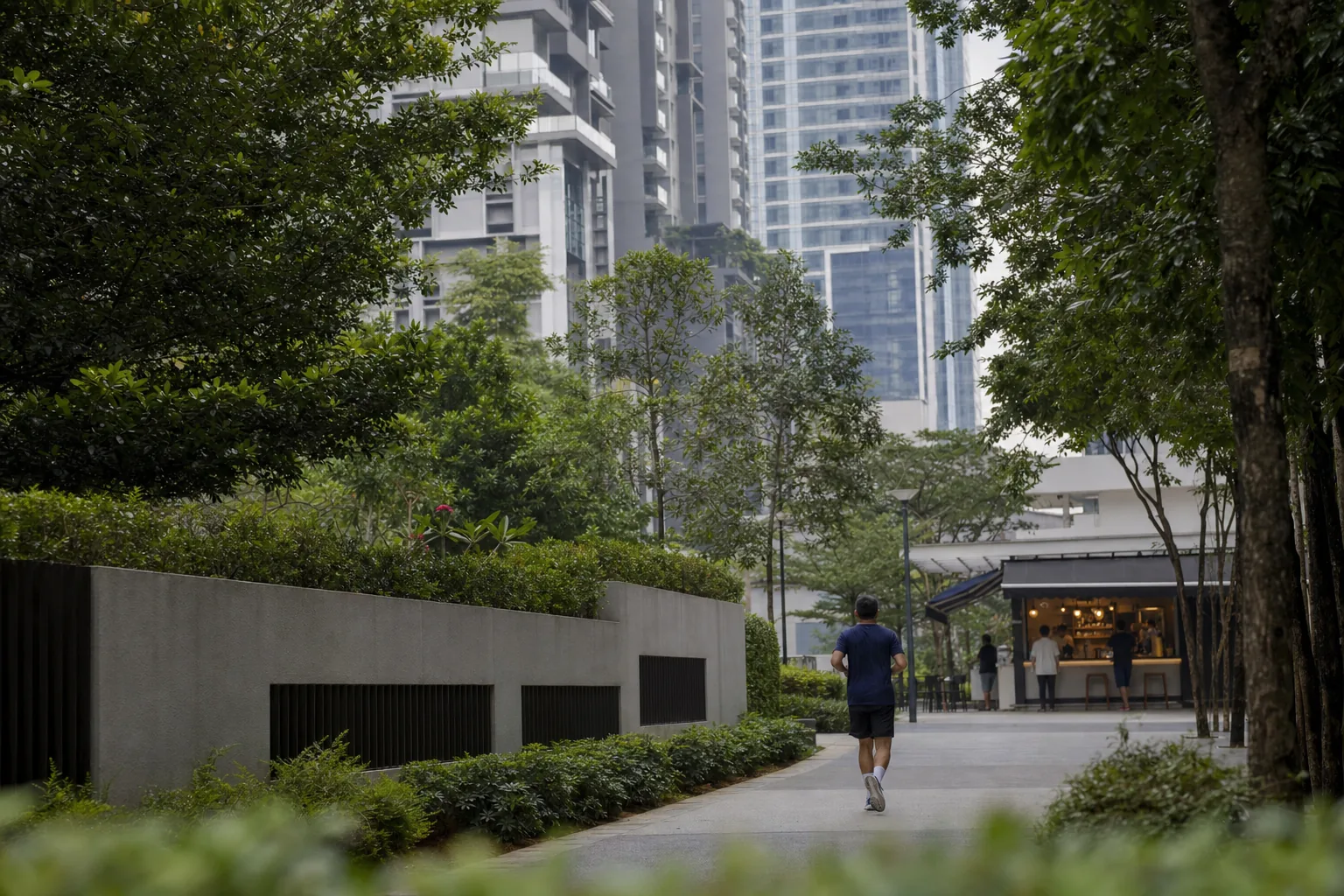 Resident jogging on a calm landscaped path among central Kuala Lumpur residential towers