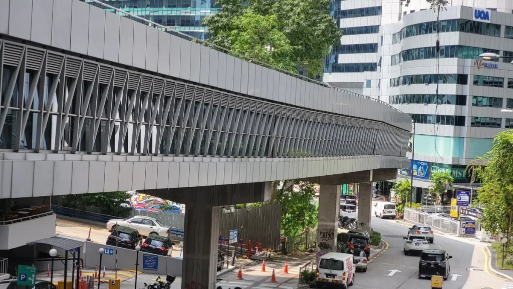 Enclosed KLCC and Bukit Bintang pedestrian bridge passing above a road beside Wisma UOA