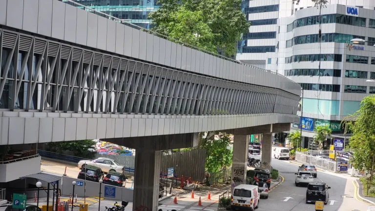 Enclosed KLCC and Bukit Bintang pedestrian bridge passing above a road beside Wisma UOA
