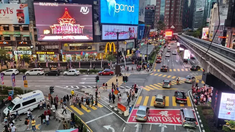 Pedestrians and traffic at the Bukit Bintang junction beneath illuminated billboards